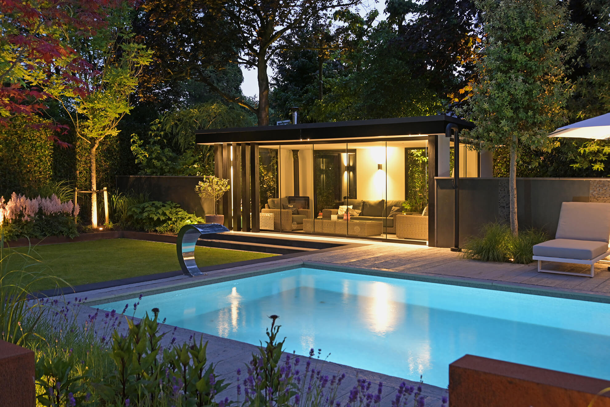 Zwembad en verlicht poolhouse aan het vlonderterras