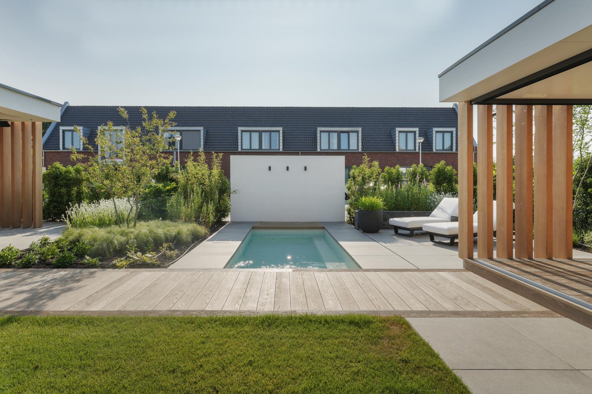 Overzicht van tuin, zwembad en terras vanuit het poolhouse