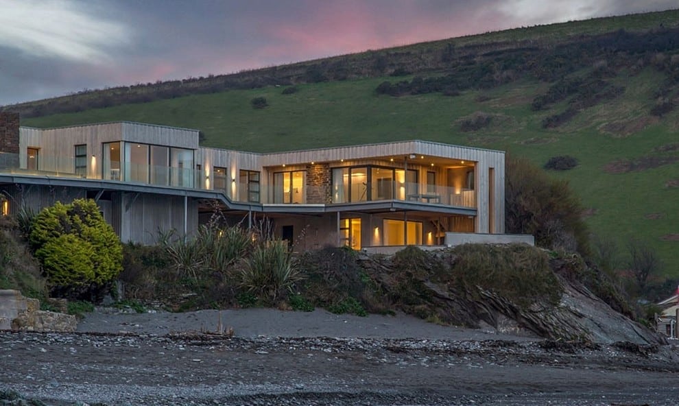 De kustwoning en het terras gezien vanaf het strand