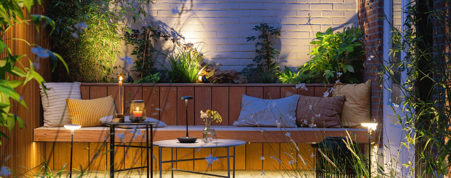 Dezelfde in-lite voorbeeldtuin met helderder licht bij de muur en beplanting