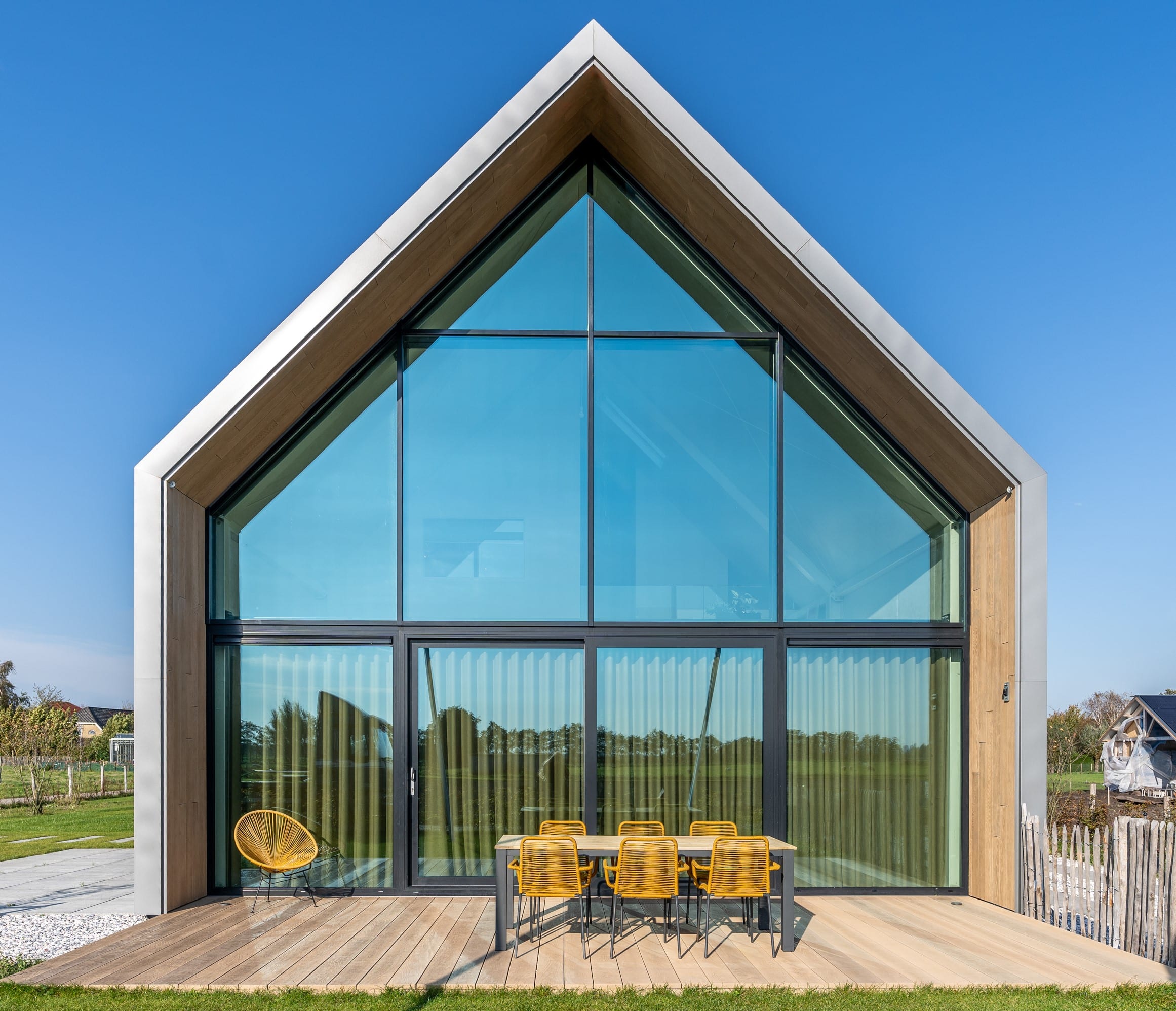 Moderne woning met een hoge glazen pui en Millboard bekleding
