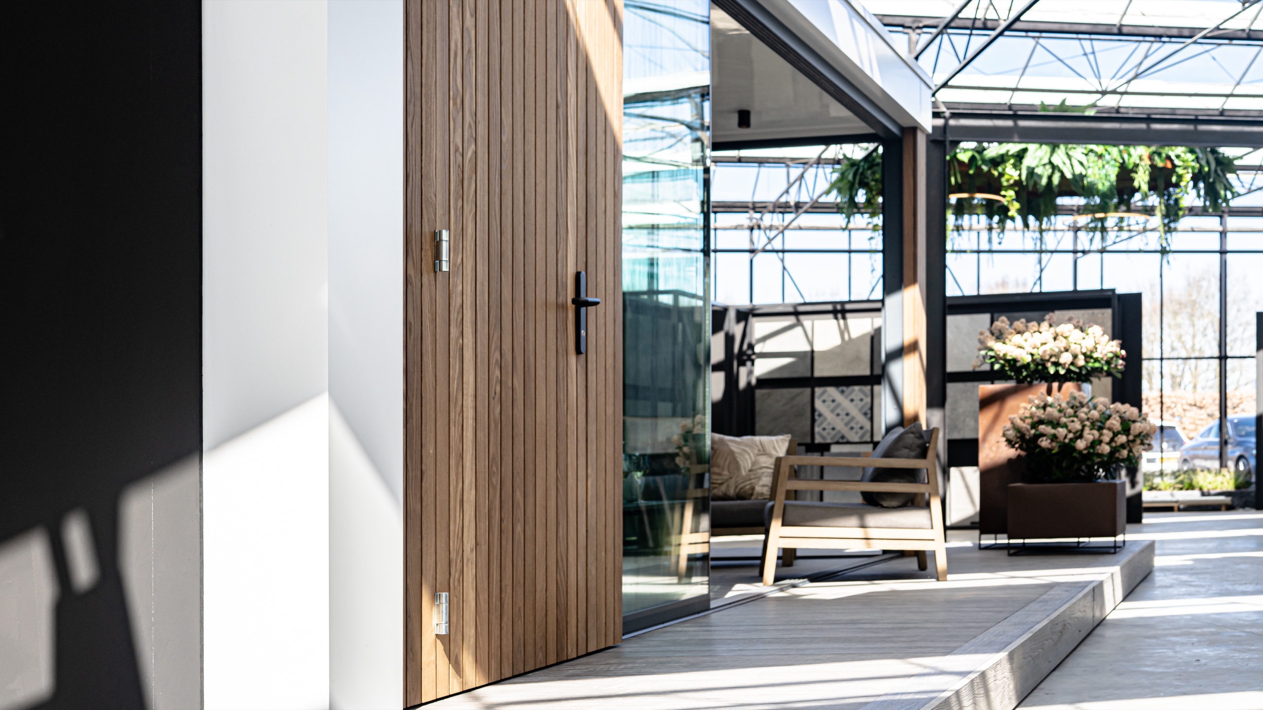Houten gevel en terras met een stoel en bloemen in de showroom van LujoGardens