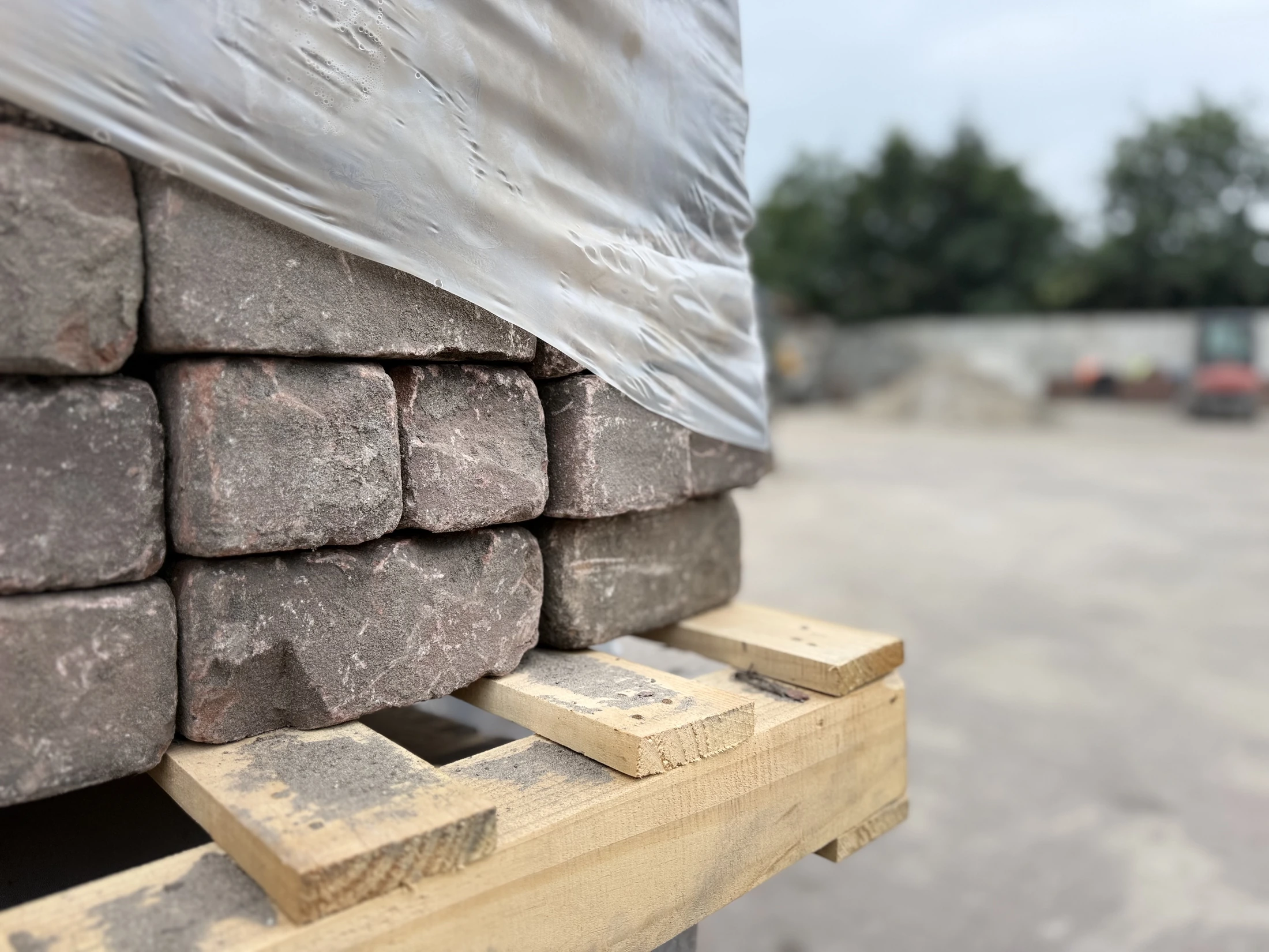 Gestapelde klinkers op een houten pallet, deels onder folie.